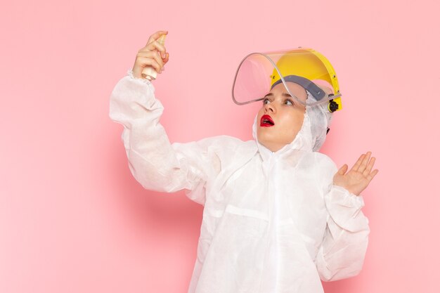 giovane bella femmina in speciale abito bianco e casco utilizzando spray sul rosa