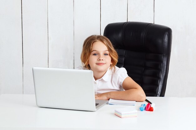 Giovane bella ragazza che si siede al posto di lavoro in ufficio.