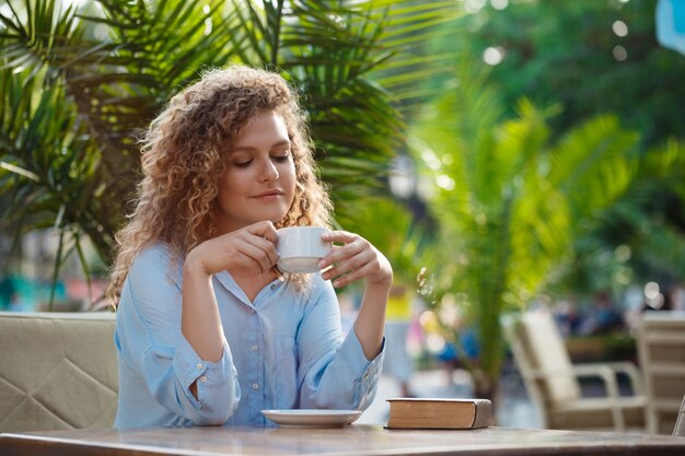 Giovane bella ragazza che si siede nella caffetteria.