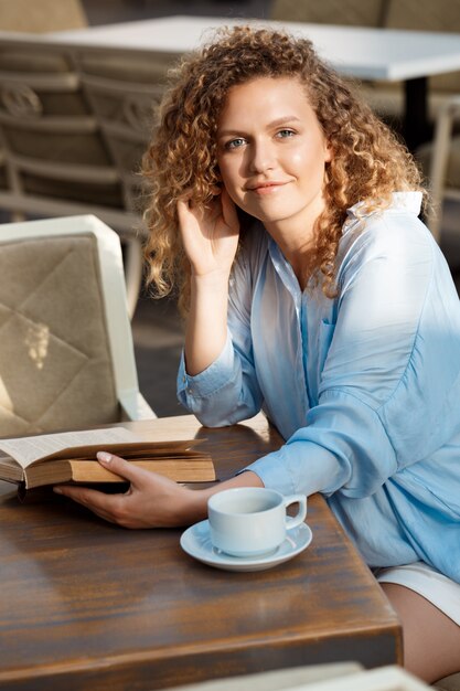 Giovane bella ragazza che si siede nella caffetteria.