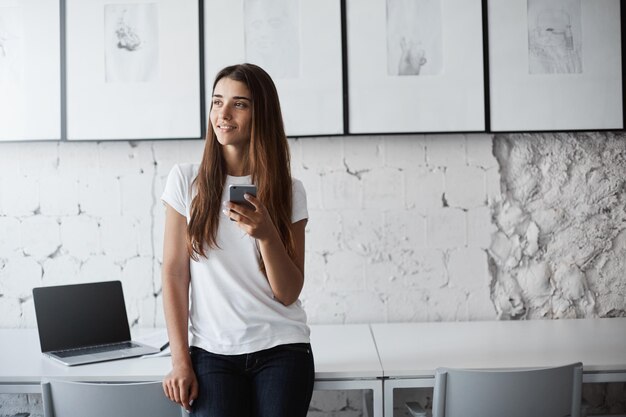 Giovane bella ragazza che utilizza lo smartphone sognando il programma di viaggio che prenota biglietti online utilizzando una carta di credito