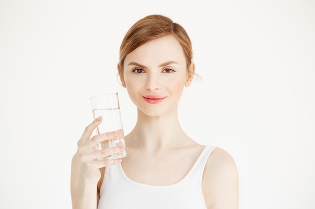 Giovane bella ragazza con pelle perfetta che sorride tenendo bicchiere d'acqua. Stile di vita di bellezza e salute.