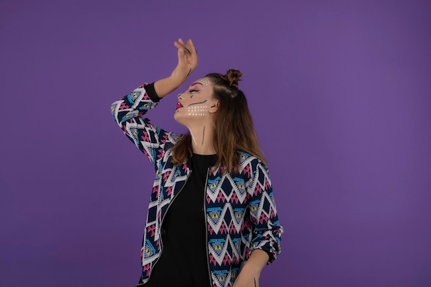 Giovane bella ragazza con trucco fantasia stand su sfondo viola. Foto di alta qualità