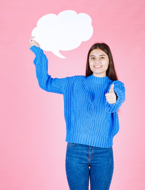 Giovane bella ragazza con una bolla bianca per il testo che mostra un pollice in su.