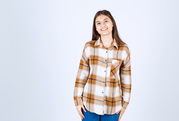 giovane bella ragazza in abito casual in piedi e in posa sul muro bianco.