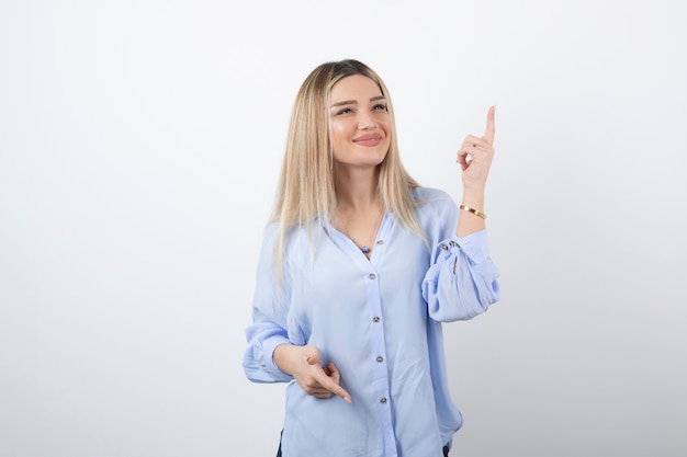 Giovane bella ragazza in piedi e in posa su bianco.