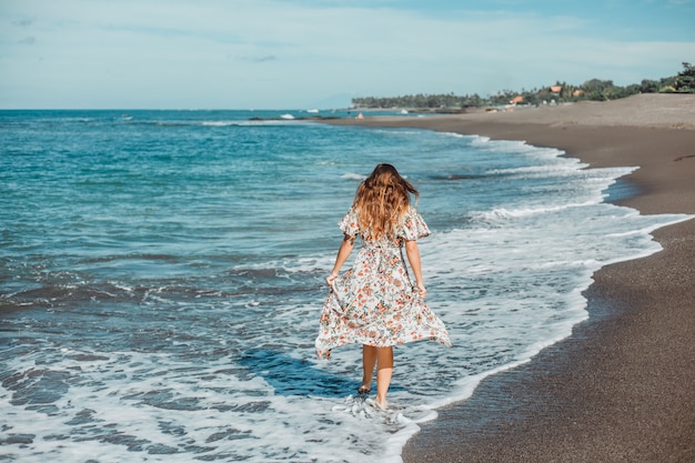 giovane bella ragazza in posa sulla spiaggia, oceano, onde, sole splendente e pelle abbronzata