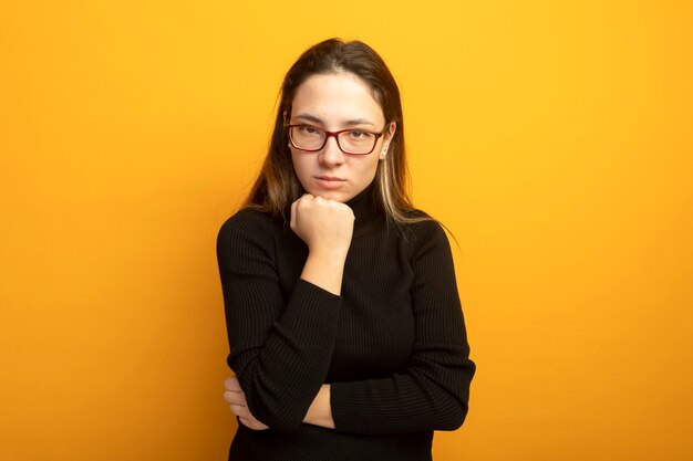 Giovane bella ragazza in un dolcevita nero con le pinne sul mento essendo dispiaciuto pensando