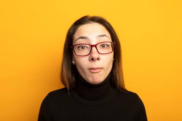 Giovane bella ragazza in un dolcevita nero sorridente con la faccia felice