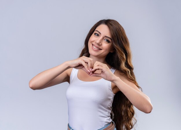 Giovane bella ragazza sorridente che fa gesto del cuore