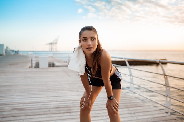 Giovane bella ragazza sportiva che si prepara all'alba sulla spiaggia.