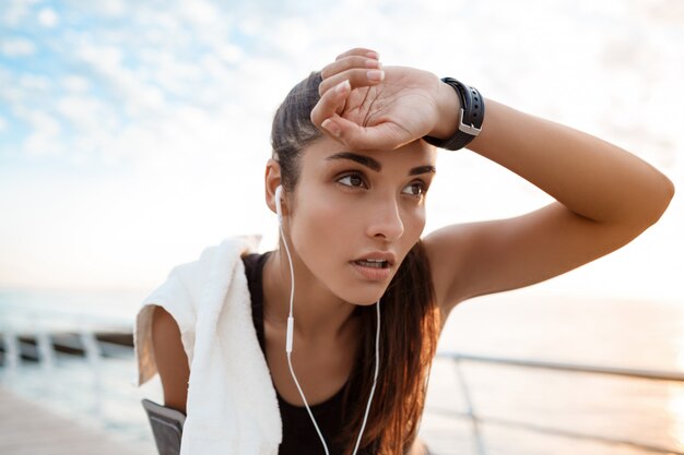 Giovane bella ragazza sportiva che si prepara all'alba sulla spiaggia.