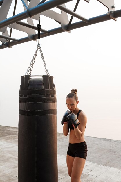 Giovane bella ragazza sportiva formazione boxe in riva al mare.