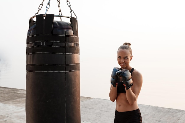 Giovane bella ragazza sportiva formazione boxe in riva al mare.