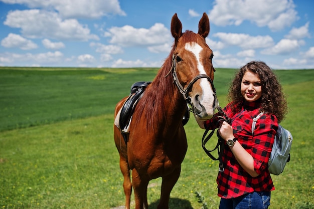 Giovane bella ragazza stare con il cavallo su un campo in una giornata di sole