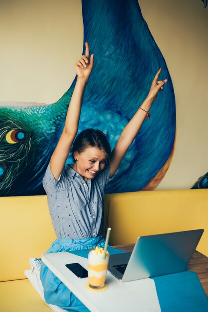 giovane bella ragazza utilizza un computer portatile nella caffetteria, navigare in internet