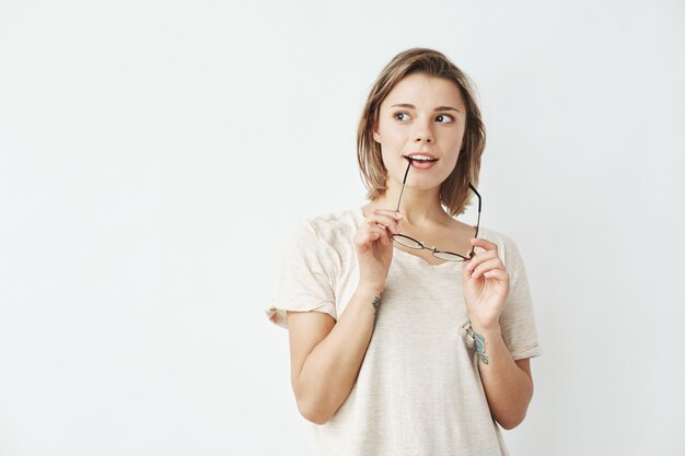 Giovane bella ragazza vaga che guarda nel pensiero laterale che tiene i vetri.