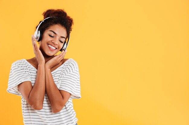 Giovane bella signora con musica d'ascolto dei capelli ricci isolata