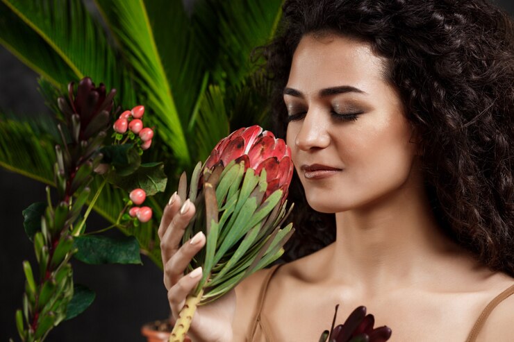 Foto gratuito giovane bellissima ragazza bruna con piante tropicali sopra la parete grigia