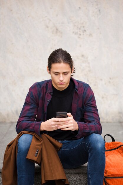 Giovane bello che controlla il suo telefono