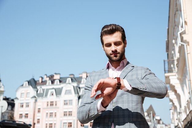 Giovane bello che controlla il tempo sul suo orologio