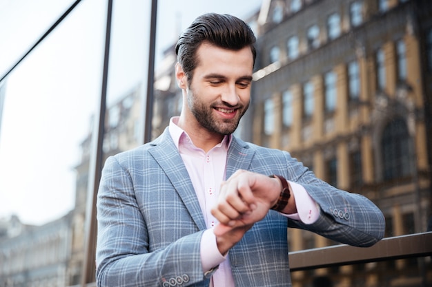 Giovane bello che controlla il tempo sul suo orologio