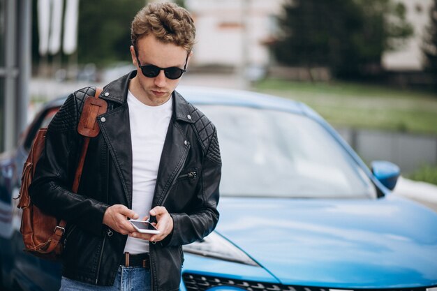 Giovane bello che per mezzo del telefono in macchina