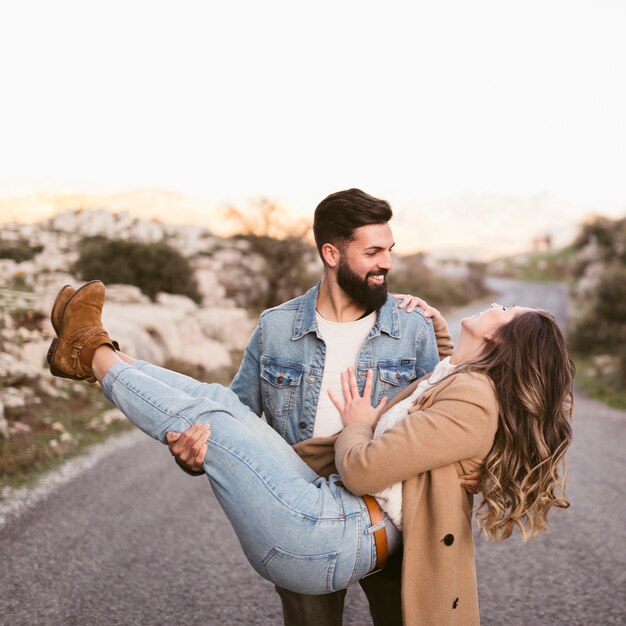 Giovane bello che trasporta la sua amica graziosa