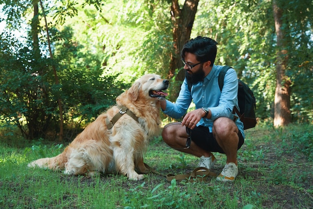 Giovane bello con il retriver dorato all'aperto