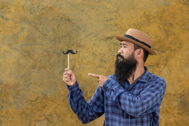 Giovane bello con la barba lunga con i baffi giocattolo