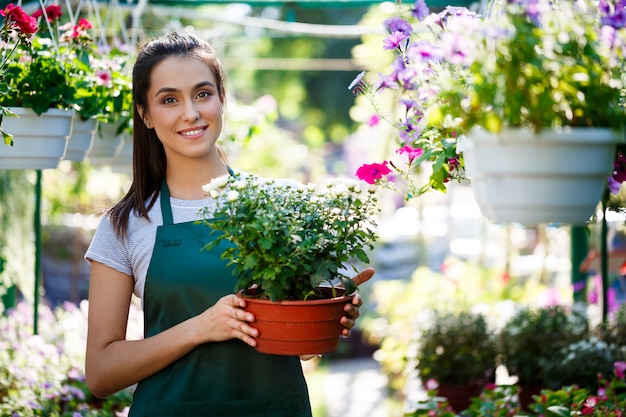 Giovane bello fiorista in posa, sorridente tra i fiori.