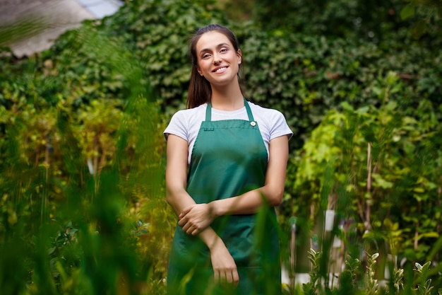 Giovane bello fiorista in posa, sorridente tra i fiori.