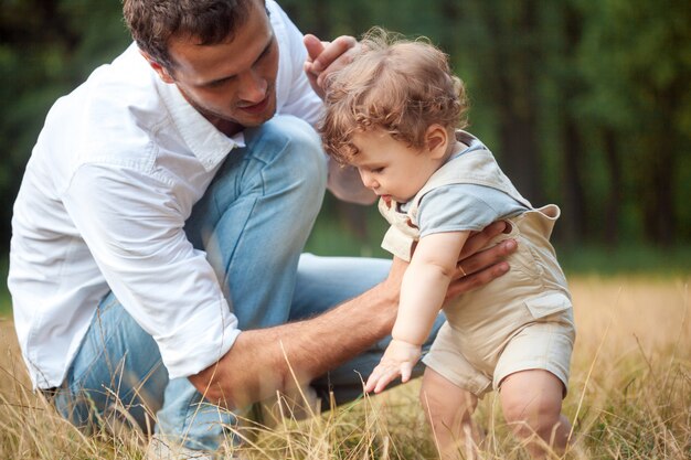 Giovane bello padre, madre e figlio piccolo del bambino contro gli alberi verdi