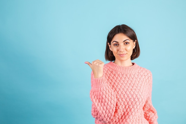 Giovane bruna in caldo maglione rosa isolato sulla parete blu