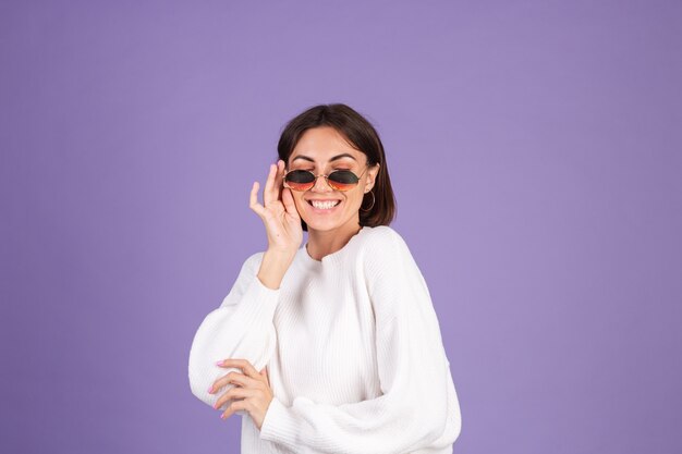 Giovane bruna in maglione casual bianco isolato sulla parete viola