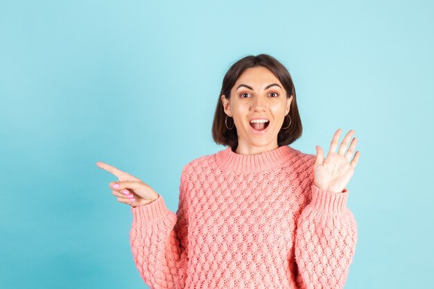 Giovane bruna in maglione rosa isolato sulla parete blu