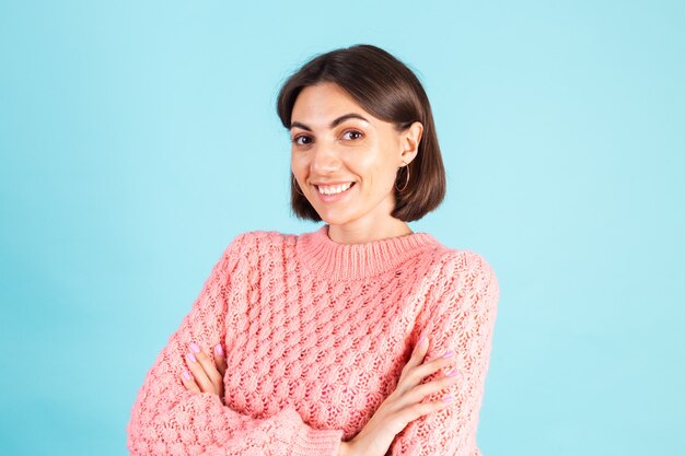 Giovane bruna in maglione rosa isolato sulla parete blu
