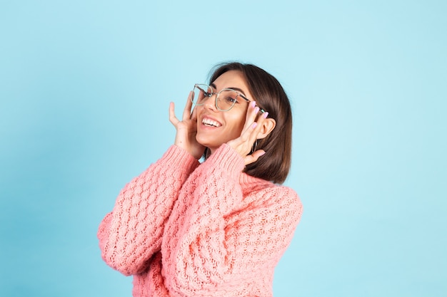 Giovane bruna in maglione rosa isolato sulla parete blu