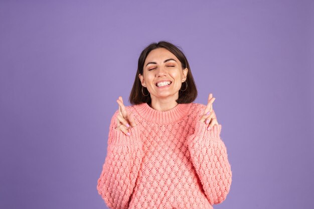 Giovane bruna in maglione rosa isolato sulla parete viola