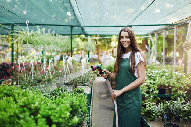 Giovane casalinga che si prende cura e innaffia piante e fiori nel suo cortile