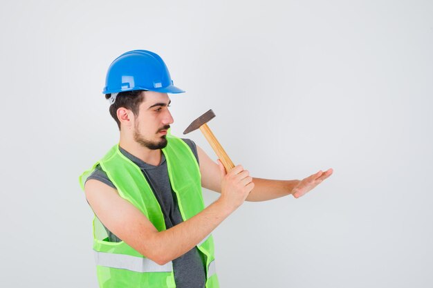 Giovane che allunga l'ascia verso la mano in uniforme da costruzione e sembra concentrato