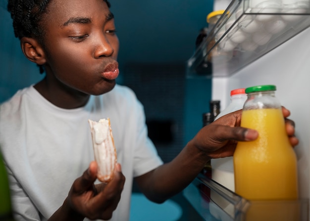 Giovane che apre il frigorifero a casa per uno spuntino nel cuore della notte