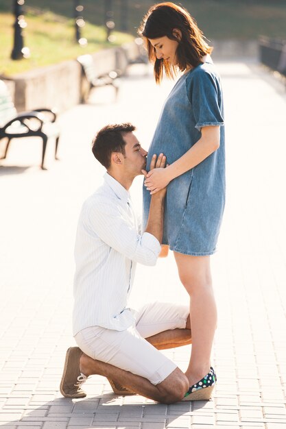 Giovane che bacia la pancia della sua moglie incinta mentre in piedi