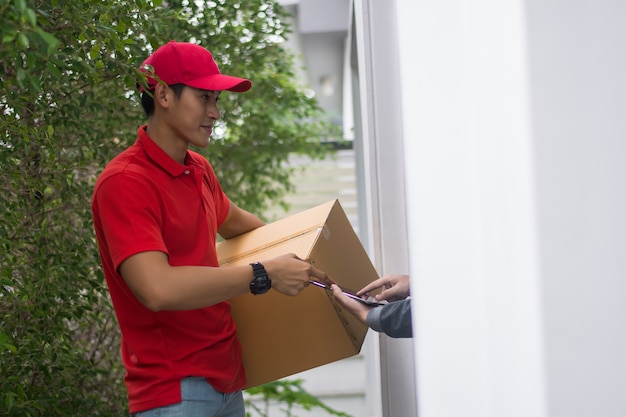 Giovane che consegna il pacchetto al cliente a casa. Consegna