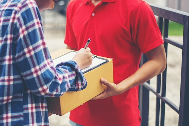 Giovane che consegna il pacchetto al cliente a casa. Consegna