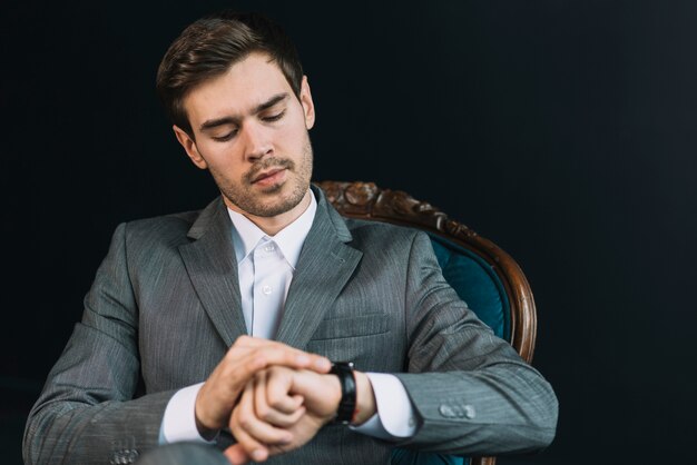 Giovane che controlla il tempo sul suo orologio su sfondo nero