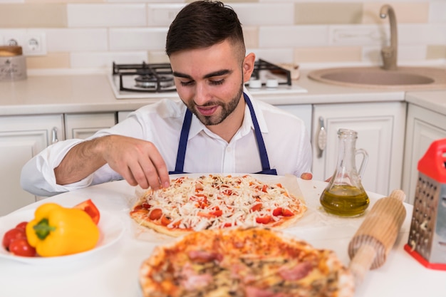 Giovane che cucina pizza in cucina