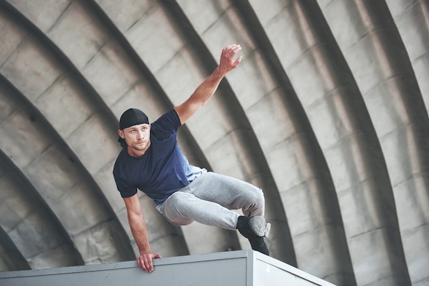 Giovane che fa il salto di parkour nello spazio urbano nella soleggiata giornata estiva di primavera della città.