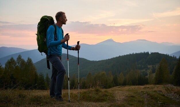 Giovane che fa un'escursione nelle montagne al tramonto