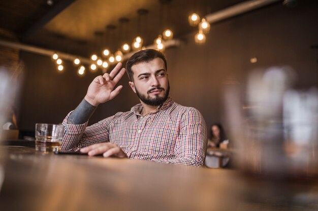 Giovane che gesturing mentre bevendo alcool alla barra